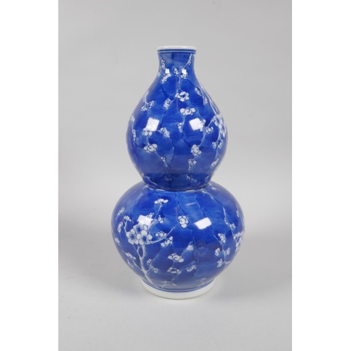 131 - A Chinese blue and white porcelain double gourd vase decorated with prunus blossom on a cracked ice ... 