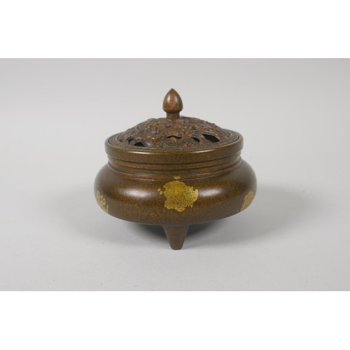 143 - A Chinese bronze censer and cover on tripod supports, with pierced lotus pond cover and gilt splash ... 