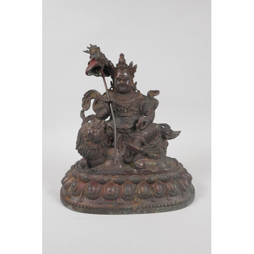 173 - A Tibetan bronze figure of Vaishravana seated on a lion's back, with the remnants of gilt patina, 23... 