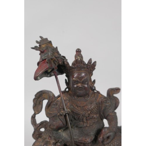 173 - A Tibetan bronze figure of Vaishravana seated on a lion's back, with the remnants of gilt patina, 23... 