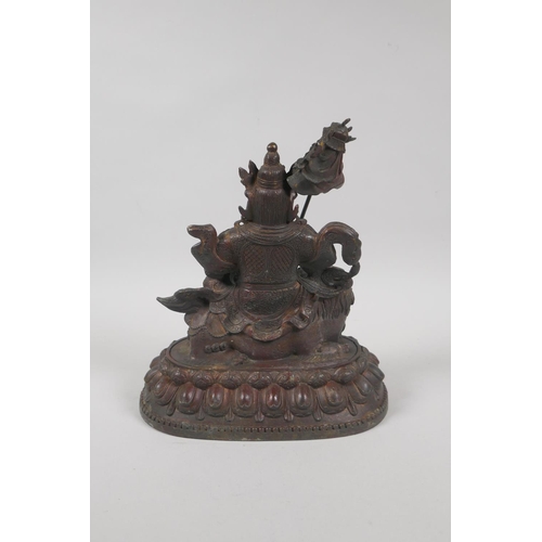 173 - A Tibetan bronze figure of Vaishravana seated on a lion's back, with the remnants of gilt patina, 23... 