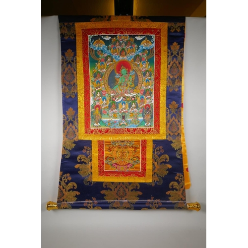 185 - A Tibetan thangka depicting green tara, in a silk hanging mount, 64cm wide