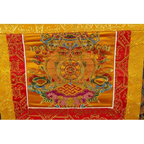 185 - A Tibetan thangka depicting green tara, in a silk hanging mount, 64cm wide