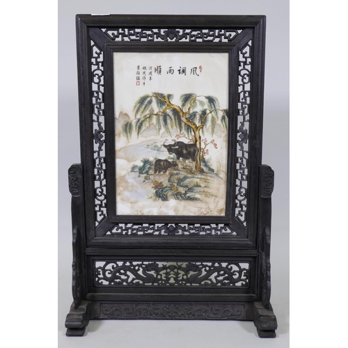 50 - A Chinese hardwood table screen with pierced fret border and inset porcelain panel painted with two ... 