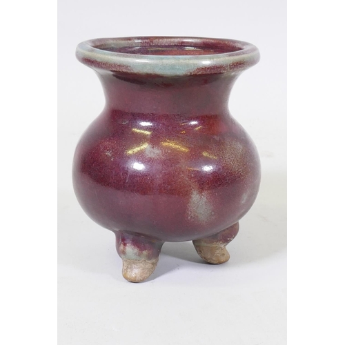 61 - A Chinese sang de boeuf flambe glazed ceramic jar on tripod supports, 16cm high