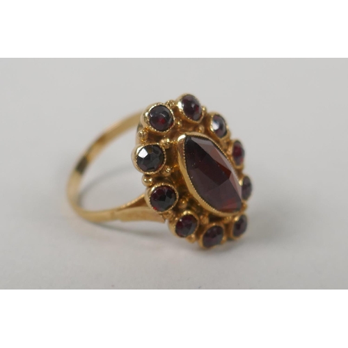 628 - A 14ct gold lady's dress ring set with a large marquise cut garnet encircled by ten smaller, size O,... 