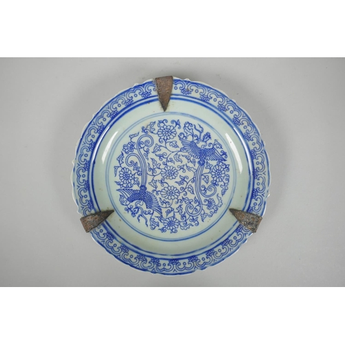 90 - A Chinese late C19th/early C20th blue and white porcelain dish with a lobed rim and phoenix decorati... 