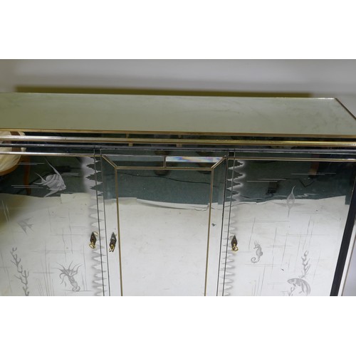 1131 - A mid century mirror glassed side cabinet, with brass mounts and stepped top over a sectional glass ... 