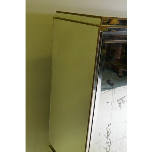 1131 - A mid century mirror glassed side cabinet, with brass mounts and stepped top over a sectional glass ... 