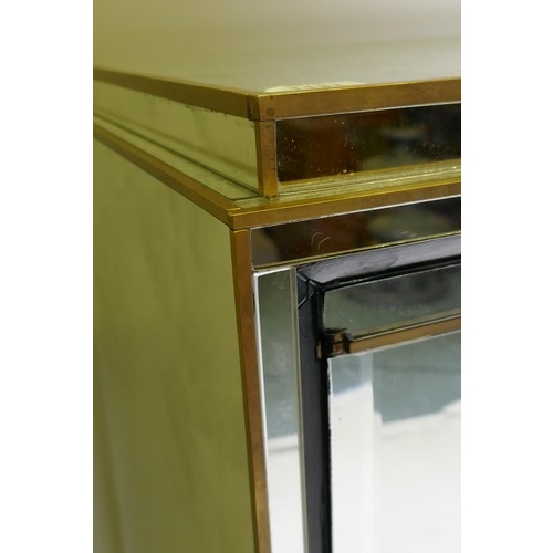 1131 - A mid century mirror glassed side cabinet, with brass mounts and stepped top over a sectional glass ... 