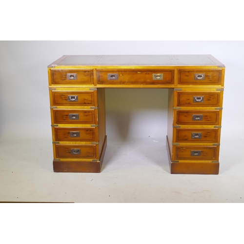 1066 - A yew wood veneered campaign style eleven drawer kneehole desk, with inset leather top and brass mou... 