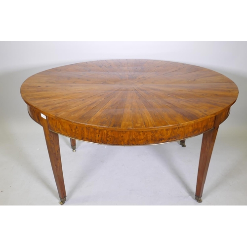 1069 - An antique yew wood oval centre table, with sunburst veneer top, the frieze with brass edge and rais... 