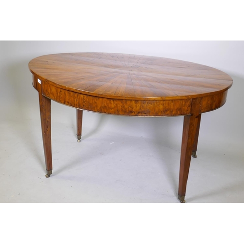 1069 - An antique yew wood oval centre table, with sunburst veneer top, the frieze with brass edge and rais... 