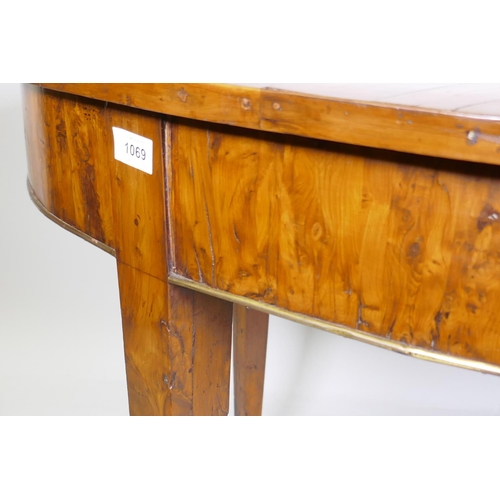 1069 - An antique yew wood oval centre table, with sunburst veneer top, the frieze with brass edge and rais... 