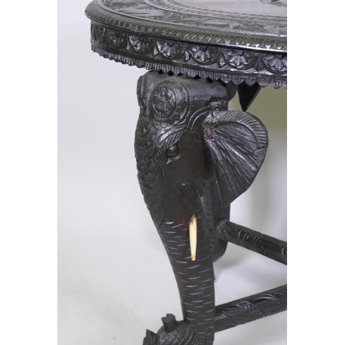 1073 - An Anglo Indian carved padouk/hardwood table, decorated with elephants and camels, raised on shaped ... 