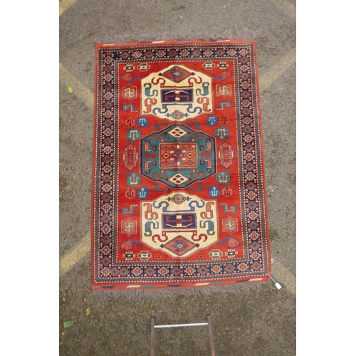 1090 - A Russian terracotta ground Kazak full pile rug with three geometric medallion design, c.1900, 130 x... 