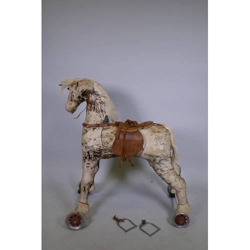 134 - Antique straw stuffed pony hide ride-on horse on wheels, 97cm high