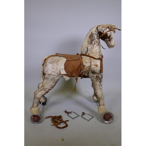 134 - Antique straw stuffed pony hide ride-on horse on wheels, 97cm high