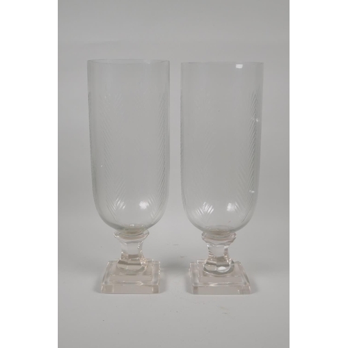 163 - A pair of moulded and cut glass hurricane vases, 34cm high