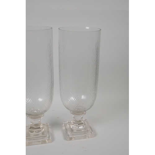 163 - A pair of moulded and cut glass hurricane vases, 34cm high