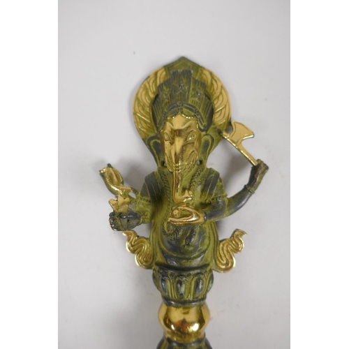 176 - A Tibetan bronze ceremonial phurba with gilt highlights and ganesh shaped handle, 32cm long