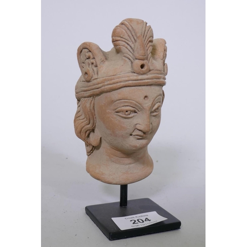 204 - A Gandhara style terracotta head of a woman wearing a headdress, mounted on a metal stand, 16cm high