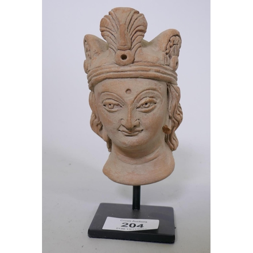 204 - A Gandhara style terracotta head of a woman wearing a headdress, mounted on a metal stand, 16cm high