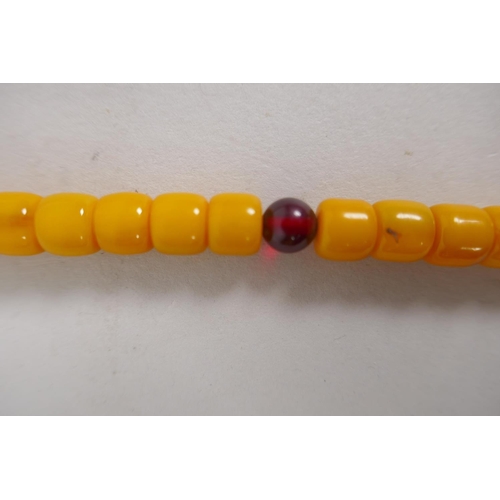 613 - A string of butterscotch amber style mala beads and a string of coral style mala beads, 80cm longest