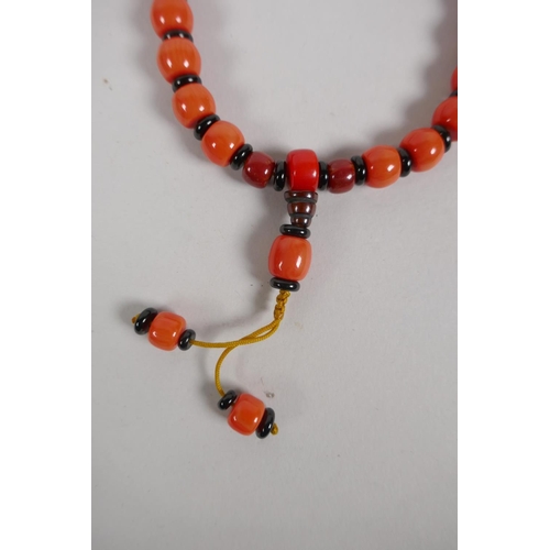 613 - A string of butterscotch amber style mala beads and a string of coral style mala beads, 80cm longest