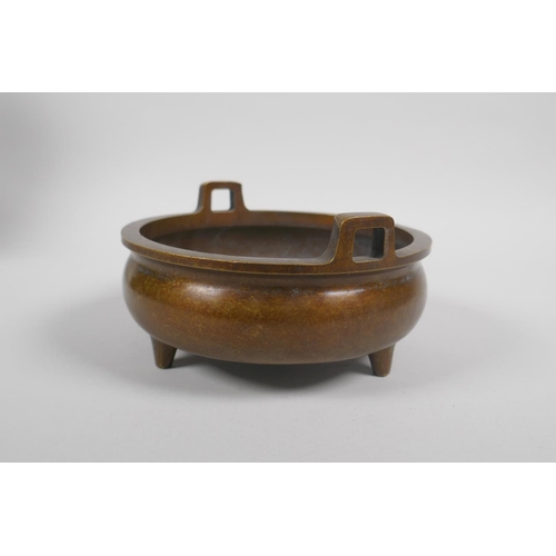 63 - A Chinese bronze two handled censer on tripod supports, 6 character mark to base, 15cm diameter