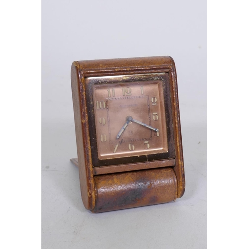 655 - A Jaeger-leCoutre travelling alarm clock, with rose coloured dial, luminescent numerals and hands, a... 