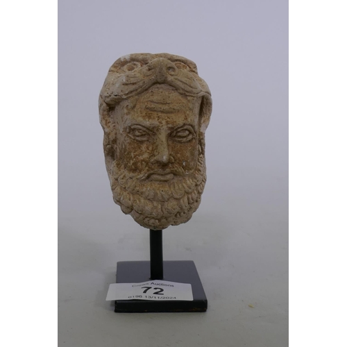 72 - A Grandhara style bust of a bearded warrior with lion skin helmet, mounted on a metal stand, 11cm hi... 