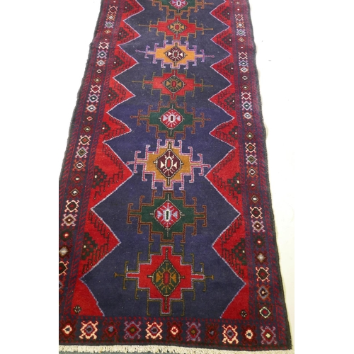 1068 - A Middle Eastern hand woven wool runner with geometric designs on a deep blue field with red borders... 