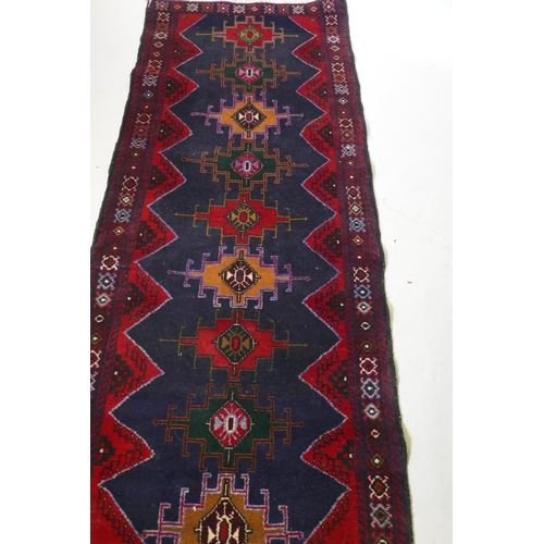 1068 - A Middle Eastern hand woven wool runner with geometric designs on a deep blue field with red borders... 