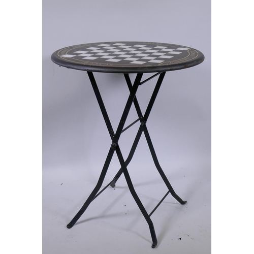 1105 - A metal bistro table with chessboard top, 61cm diameter, 73cm high