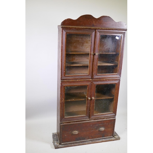 1151 - A C19th stained pine shop cabinet, two pairs of glazed doors over a single drawer, 87 x 29 x 153cm