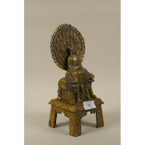 12 - An Oriental brass figure of Buddha seated upon two lions with a flaming aureola, inscribed verso, 28... 