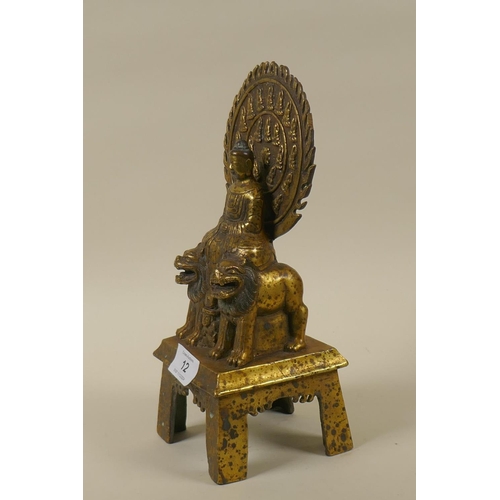 12 - An Oriental brass figure of Buddha seated upon two lions with a flaming aureola, inscribed verso, 28... 