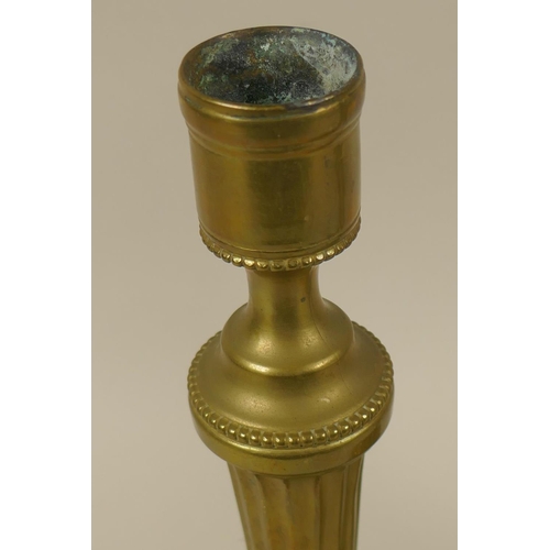 50 - A pair of antique brass candlesticks with fluted columns and bead decoration, 26cm high