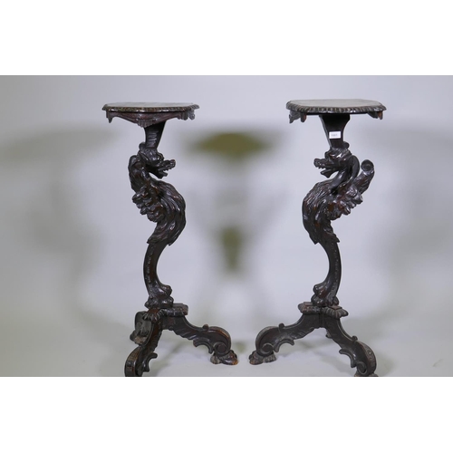 1001 - A pair of stained and carved pine stands in the form of griffins, raised on tripod supports, possibl... 