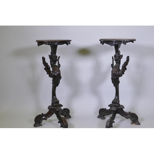 1001 - A pair of stained and carved pine stands in the form of griffins, raised on tripod supports, possibl... 