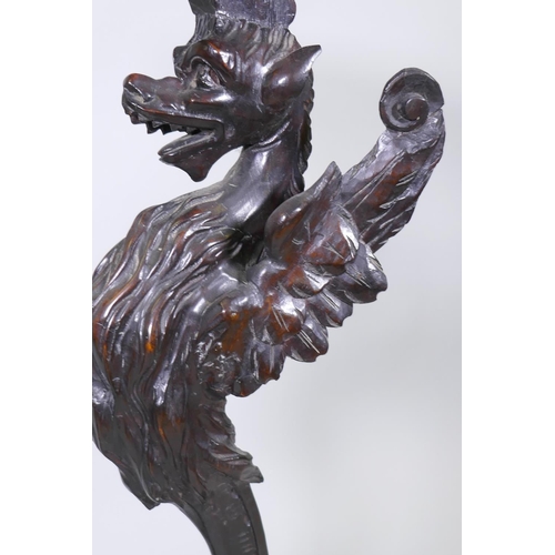 1001 - A pair of stained and carved pine stands in the form of griffins, raised on tripod supports, possibl... 