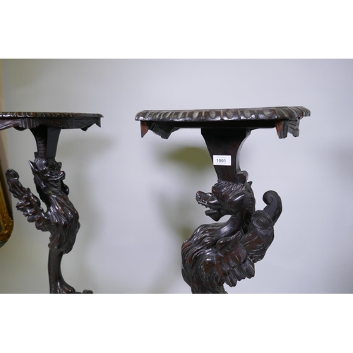 1001 - A pair of stained and carved pine stands in the form of griffins, raised on tripod supports, possibl... 