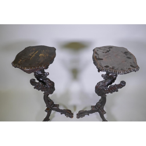 1001 - A pair of stained and carved pine stands in the form of griffins, raised on tripod supports, possibl... 