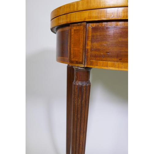 1007 - A Georgian mahogany D shaped card table, with cross banded top and frieze, raised on reeded tapering... 