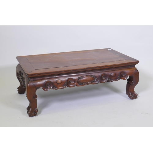 1014 - A Chinese rosewood low table, with inset panel top and finely carved scrolled frieze, raised on shap... 