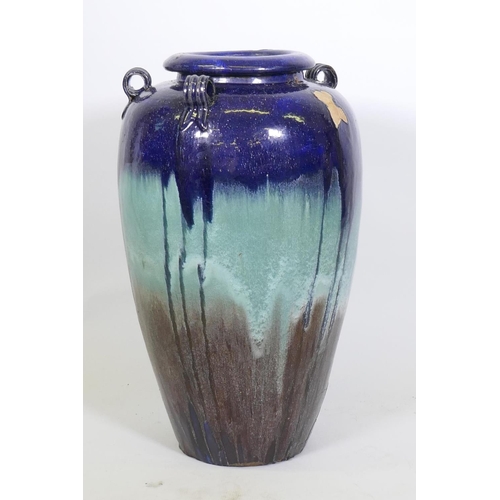 1063 - A blue drip glazed terracotta floor vase with lug handles, one missing, 73cm high