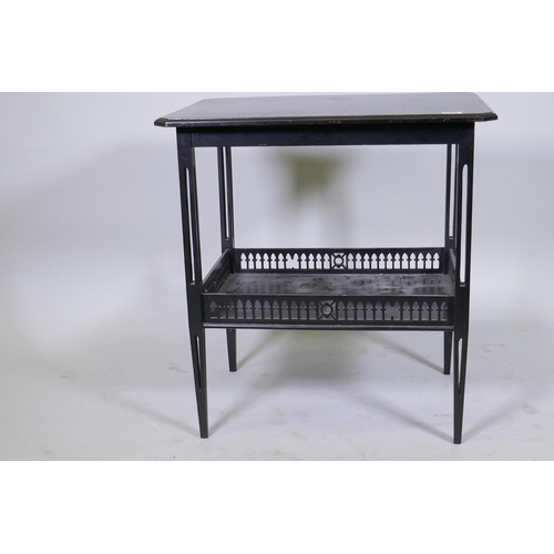 1083 - A Victorian Arts & Crafts style two tier occasional table with pierced tapering supports and got... 