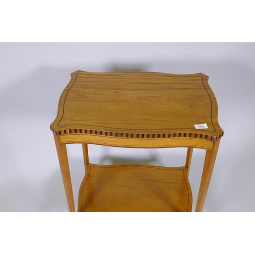 1096 - A Sheraton style satinwood and ebony inlaid serpentine shaped two tier occasional table, raised on s... 