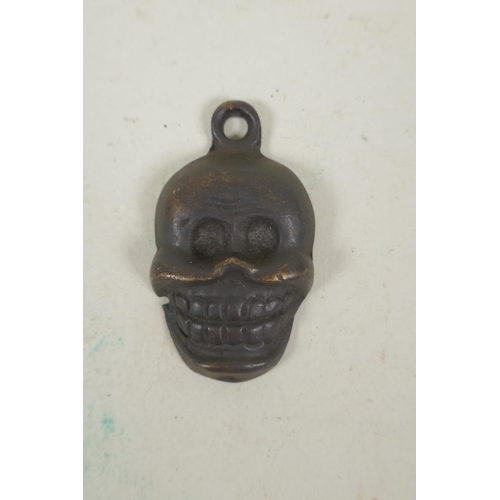 254 - A Tibetan bronze citipati death mask pendant, and a pendant in the form of a wrathful deity